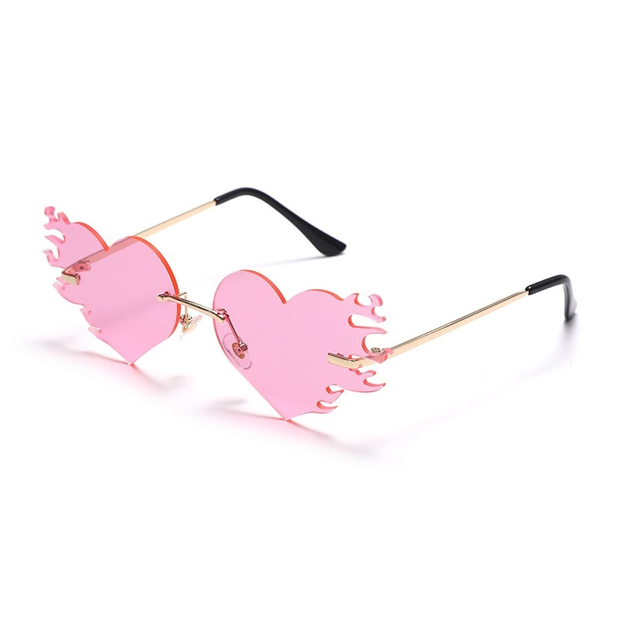 A stylish pair of frameless sunglasses in a heart shape, perfect for adding a touch of flair to any outfit. The lenses are a fiery red color, giving them a unique and bold look. Perfect for making a statement and standing out from the crowd.